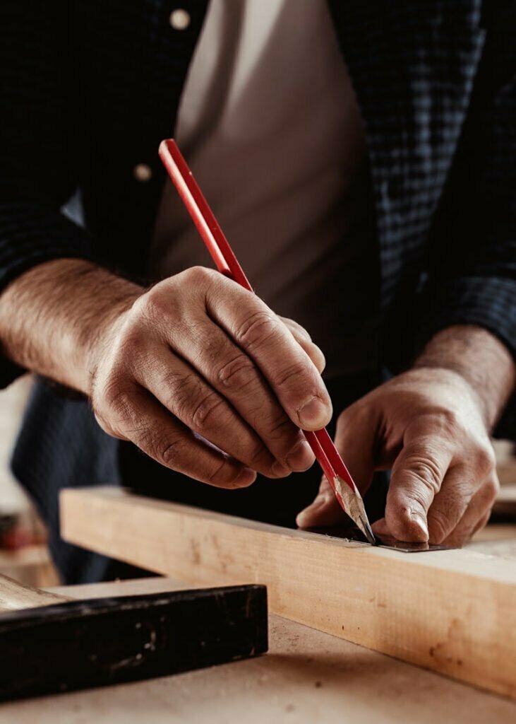 Carpenter makes pencil marks on a wood plank