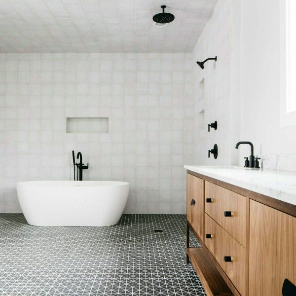 Custom made bathroom vanity with beautiful wood grain detailing, black and white tile floors, and a large white bathtub.